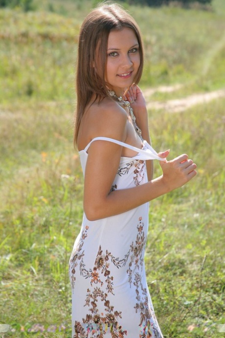 Petite white girl Rita B models naked in a farmer's field