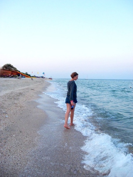 Amateur girl with red hair changes into a bikini before getting in the ocean