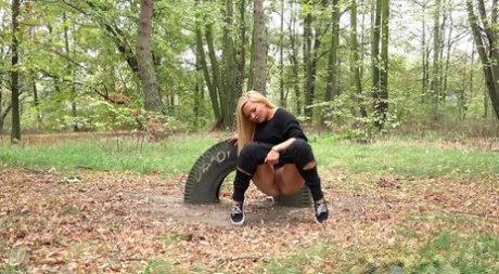 Blonde girl Jenna Lovely takes a pee on leaf strewn ground at a park
