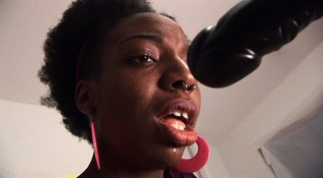 Naked black girl Sage sucks on a black dildo before pissing in a glass bowl