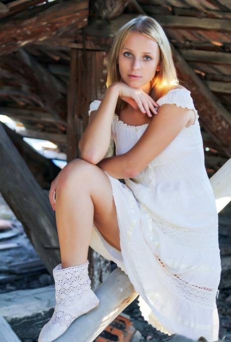 Young blonde Ilona D gets naked in a rustic setting with her boots on