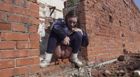 Vika Lita pulls down her pants to pee at what's left of a brick building