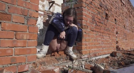 Vika Lita pulls down her pants to pee at what's left of a brick building