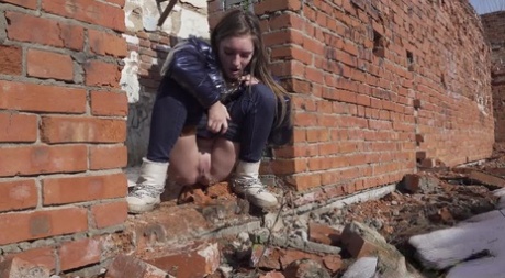 Vika Lita pulls down her pants to pee at what's left of a brick building