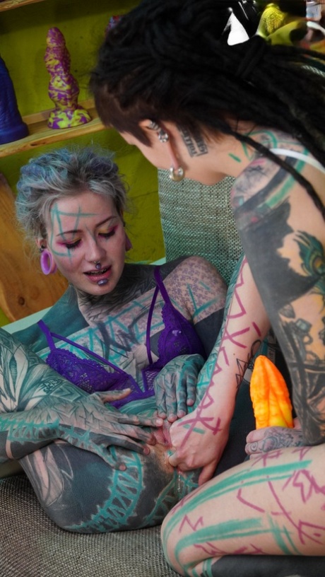 Heavily tattooed girls engage in anal play during GGB sex on a sofa