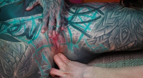 Heavily tattooed girls engage in anal play during GGB sex on a sofa