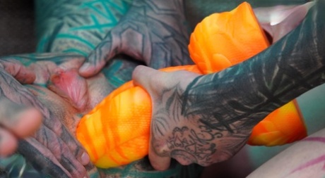 Heavily tattooed girls engage in anal play during GGB sex on a sofa
