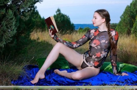 Young beauty Dariana gets butt naked outdoors on a blanket while reading