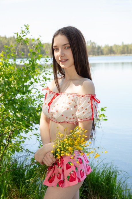 Adorable teen Ernesta frees her full breasts while going nude near the water