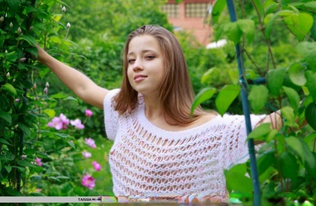 Pretty faced teen Taissia A flashing tiny boobs outdoors in the garden