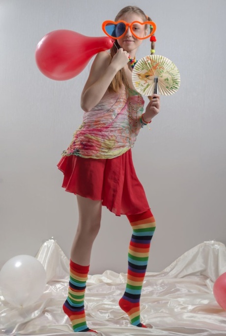 Skinny teen girl in pigtails and multi-colored socks takes off her clothes