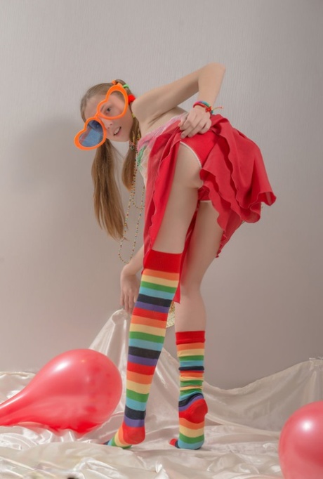Skinny teen girl in pigtails and multi-colored socks takes off her clothes