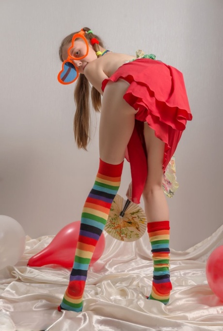 Skinny teen girl in pigtails and multi-colored socks takes off her clothes