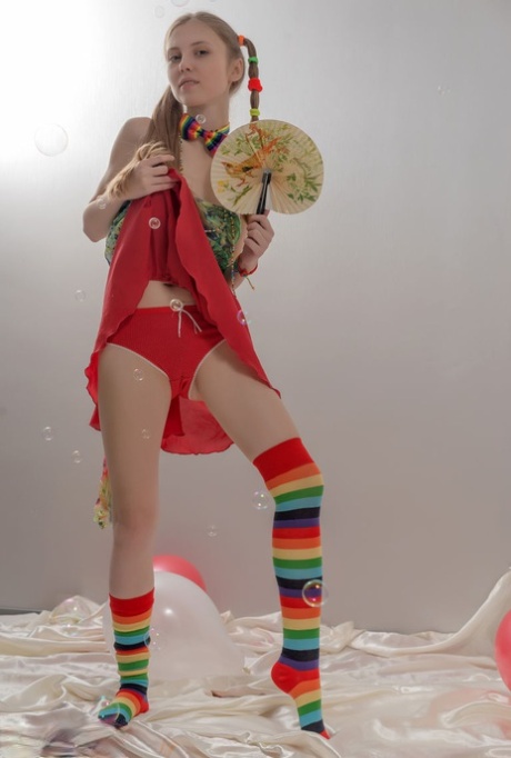 Skinny teen girl in pigtails and multi-colored socks takes off her clothes