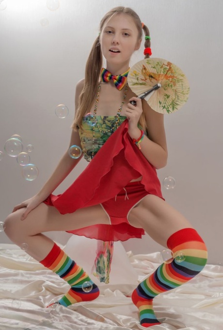 Skinny teen girl in pigtails and multi-colored socks takes off her clothes