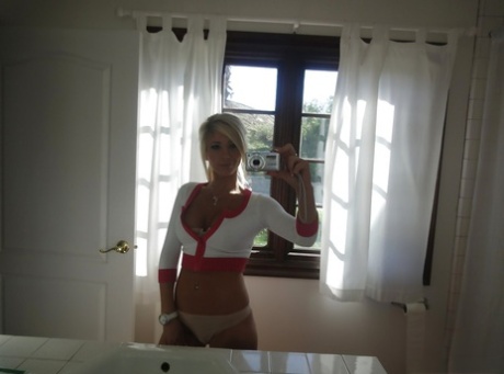Blonde female Tasha Reign taking mirror self shots while removing her clothes