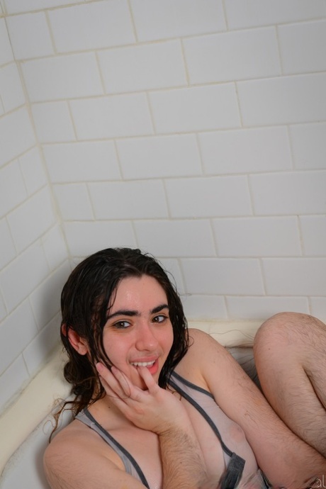 Hairy seductress Kisa Fae strips in the bathtub and washes herself