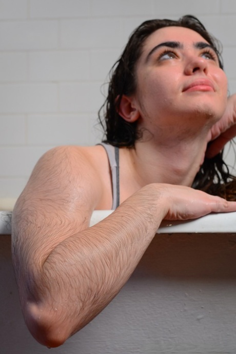 Hairy seductress Kisa Fae strips in the bathtub and washes herself