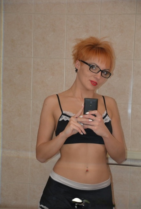 Redheaded MILF strips her maid uniform and poses naked in the bathtub