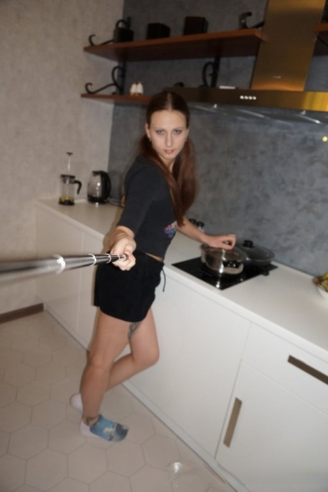 Brunette amateur with a ponytail uses a selfie stick to take semi-nude pics